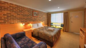 Queen bed and lounge chairs in a guest room at the Jumbuck Motor Inn