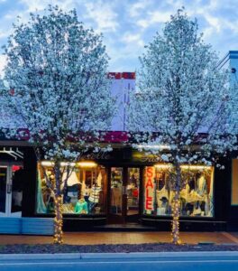 Sherelle Fashions shopfront lit up behind street trees in Tenterfield