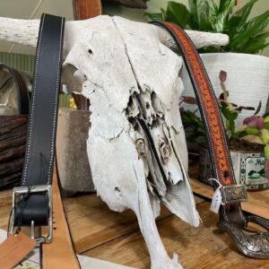 Tooled leather belts draped over a cattle skull at Matilda Made Leather