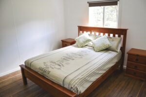 Timber-framed bed with cream linen at Four Bull Hut