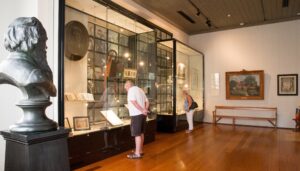 Visitor viewing the museum exhibits beside a bronze bust of Sir Henry Parkes, School of Arts Tenterfield