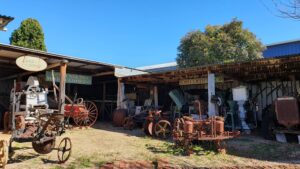 Vintage tractors and farm implements under a shelter at Centenary Cottage Museum