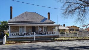 Street view of Centenary Cottage Museum, a stone cottage with a verandah in Tenterfield