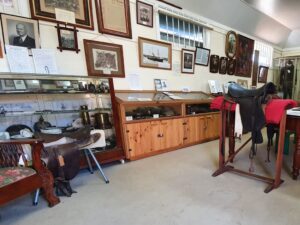 Museum room with saddle, display cases and historic photographs at Centenary Cottage Museum