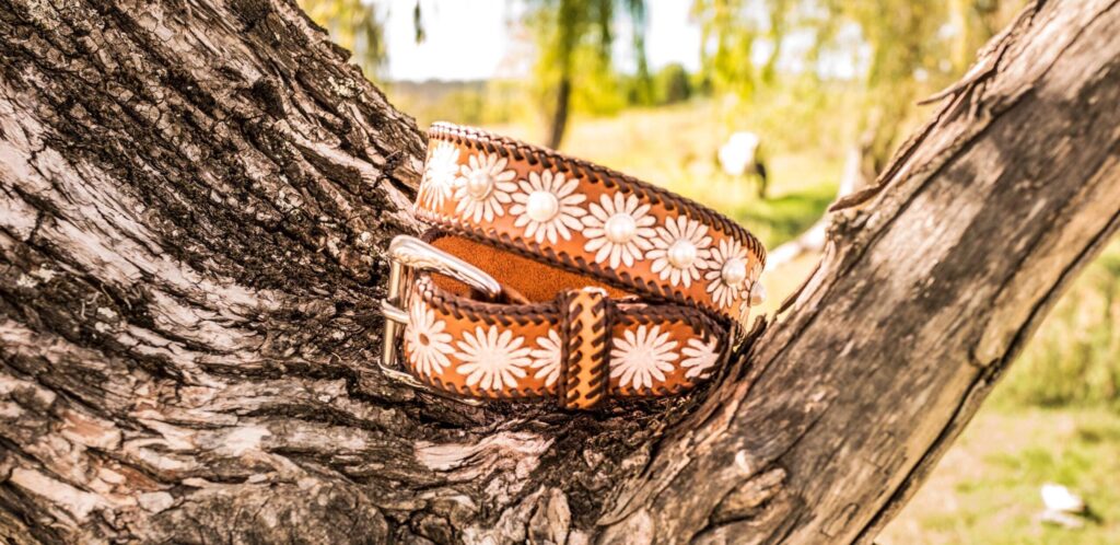 Hand-tooled leather belt resting on a weathered branch, Matilda Made Leather