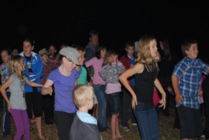 Group of kids and families dancing at a night gathering at Levuka