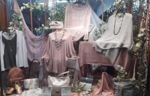 Window display of soft pink knitwear and accessories at Sherelle Fashions