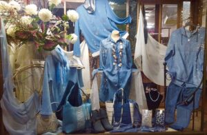 Window display of denim outfits and summer bags at Sherelle Fashions