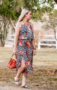Model in a blue floral wrap dress with red handbag from Sherelle Fashions