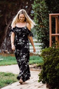 Model walking in a black floral maxi dress from Sherelle Fashions