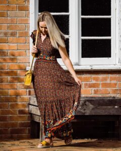 Model in a brown boho maxi dress against a brick wall, Sherelle Fashions