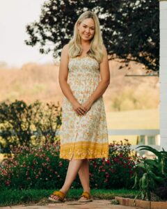 Model in a yellow-trimmed white sundress in the garden, Sherelle Fashions