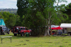 Vehicles and rooftop tents in the riverside camping area at Levuka