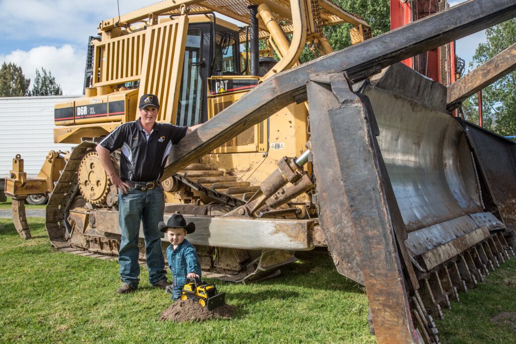 Father and child standing beside AB Contracting earthmoving machinery