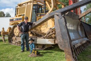 Father and child standing beside AB Contracting earthmoving machinery