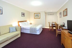 Suite with queen bed and lounge at The Henry Parkes Motel