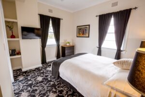 Queen room with patterned carpet and dark drapes at The Commercial Boutique Hotel