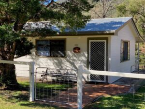 White farm cottage behind a picket fence at Wangrah Wilderness Lodge