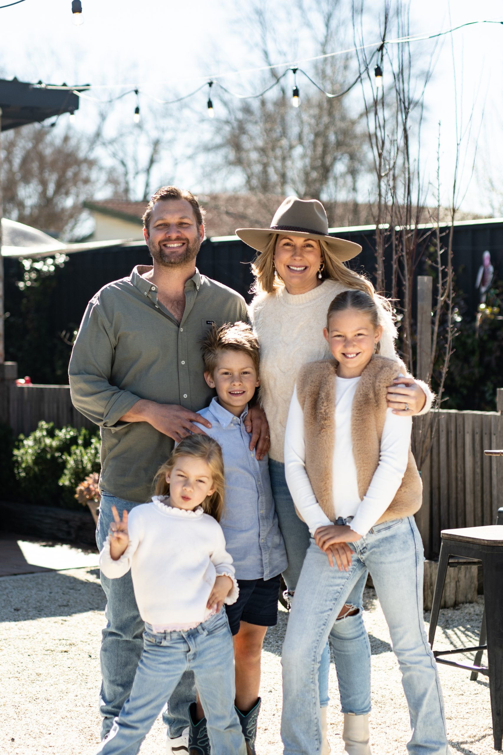 A family of five smiling together in a sunny courtyard in Tenterfield