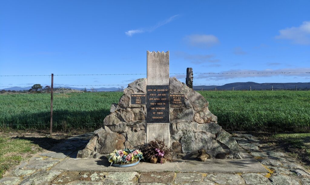 Stone cairn memorial to the F-111 crash with flowers laid at its base, near Tenterfield