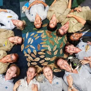 Guides lying in a circle around a leaf mandala, the Journey Outdoors in Nature team