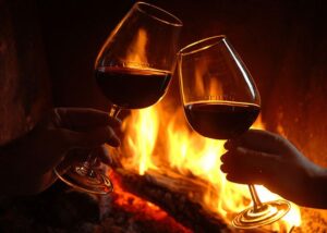 Two glasses of red wine raised by the open fire at The Commercial Boutique Hotel