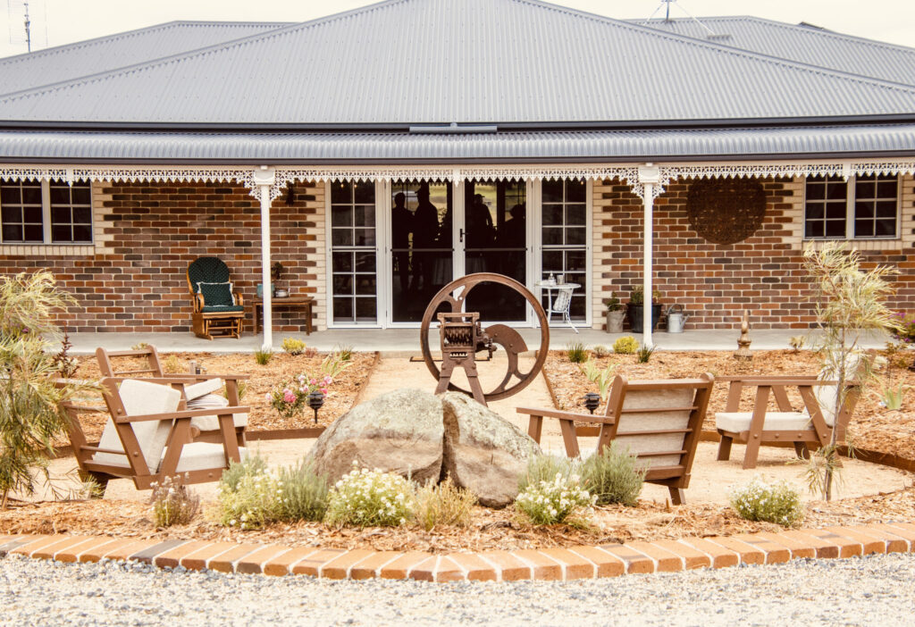 Brick guesthouse with verandah and landscaped courtyard seating at Carpe Diem Guesthouse Tenterfield