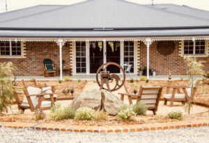Brick guesthouse with verandah and landscaped courtyard seating at Carpe Diem Guesthouse Tenterfield