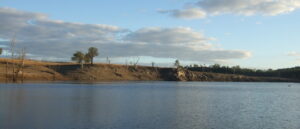 Still water and steep banks of Glenlyon Dam at dusk