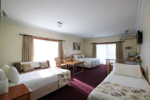 Family room with multiple beds at The Henry Parkes Motel