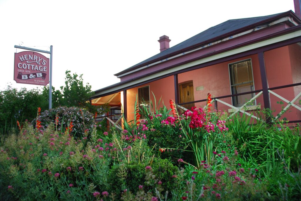 Henry's Cottage B&B, a historic pink cottage behind flowering gardens