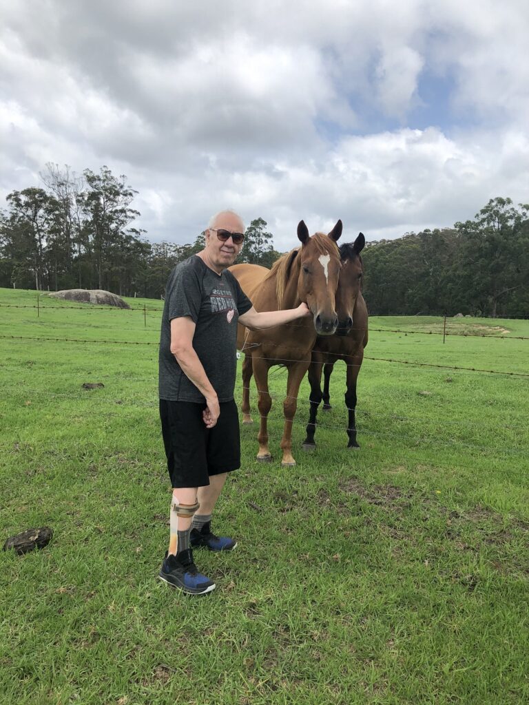 Man standing with two horses in a green paddock, horse riding in Tenterfield