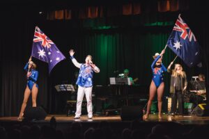 Performers waving Australian flags on stage at the Tenterfield Cinema and Theatre