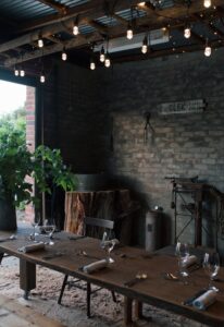 Outdoor brick fireplace and dining table strung with festoon lights at the Old Council Chambers
