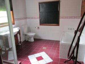 Ensuite bathroom with pink tiled floor and bathtub at Henry's Cottage