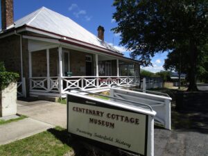 Centenary Cottage Museum entrance sign and stone cottage in Tenterfield