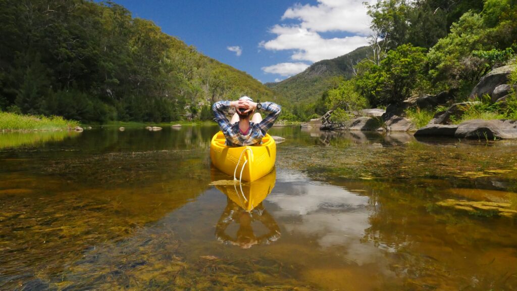Kayaker paddling a yellow kayak up a clear river gorge with Journey Outdoors in Nature
