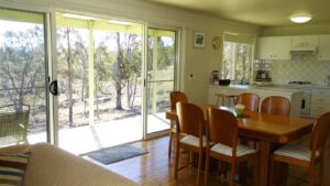 Sunlit dining room opening onto bushland views at Mistral Hill Country Cottage
