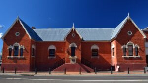 Red brick facade of the Sir Henry Parkes Memorial School of Arts under a blue sky