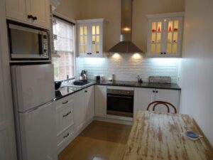 Modern white kitchen with timber table in Red Rose Cottage