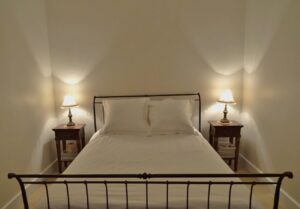 Iron-framed bed with bedside lamps in Red Rose Cottage