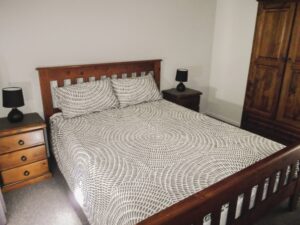 Queen bed with timber bedhead inside Robinsons Cabin