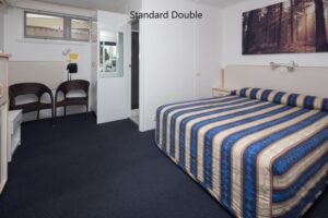 Standard double room with striped bedspread at the Tally Ho Motor Inn