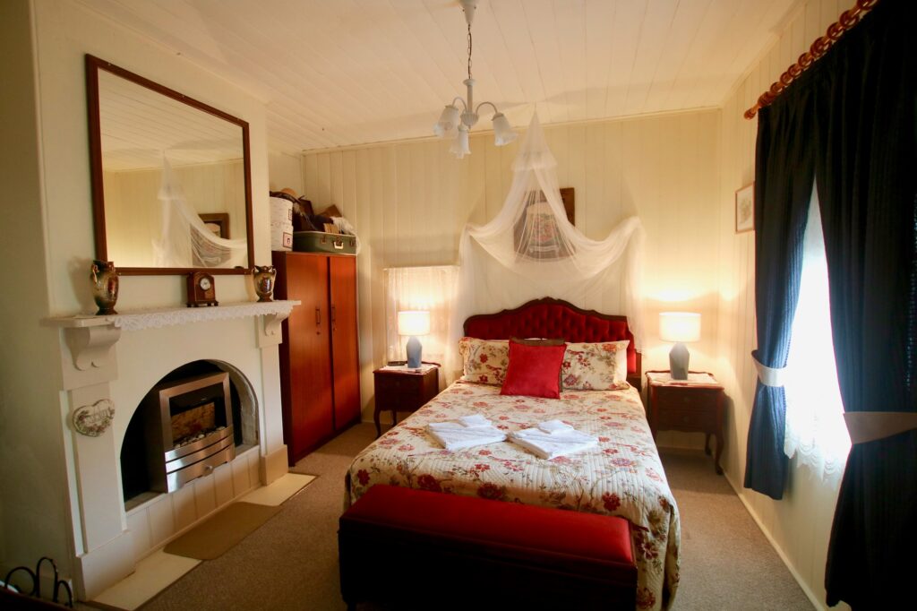 Bedroom with canopy drapes and marble fireplace at Tenterfield Cottage