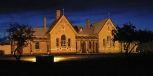 Sandstone Tenterfield railway station building floodlit at dusk