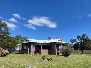The Brown House Tenterfield, a weatherboard farmhouse on a sunny lawn