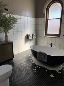 Black freestanding bath under an arched window in the Old Council Chambers bathroom