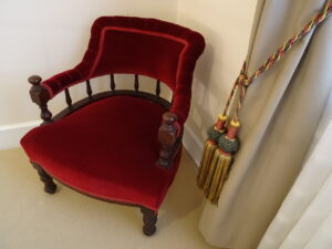 Red velvet antique chair with tasselled curtain tie at White & Red Rose Cottages