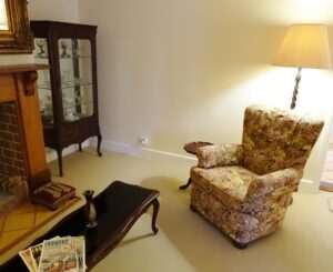 Sitting room with armchair and antique display cabinet at White & Red Rose Cottages