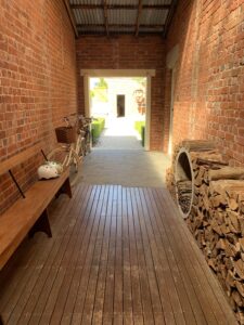 Brick walkway lined with firewood leading through the Old Council Chambers
